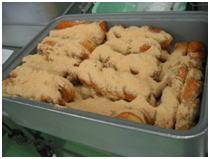 バットに並べられた揚げパンにたっぷりと黒豆きなこがまぶされている写真