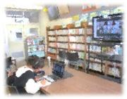 多数の本棚がある部屋で一人の女性が机の上で本を読んでいる写真