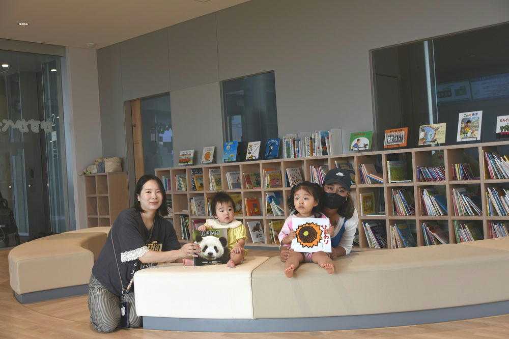 かすかべっ子ルームに遊びに来ていた親子が寄贈された絵本を手に持った写真