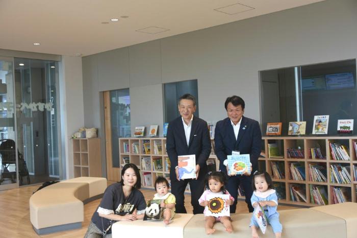 寄贈絵本を手に持ったこどもたちと、菅野社長と岩谷市長の写真