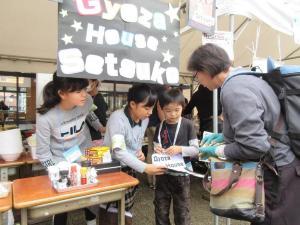 露店で女の子が年配の男性に物を売っている写真