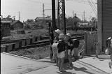 踏切の前に立っているランドセルを背負った小学生の白黒写真