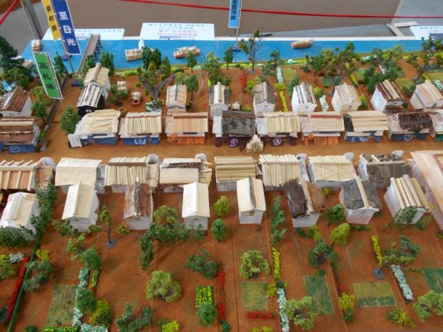 川のふもとに店や住宅が立ち並ぶミニチュア模型の写真