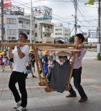 街道で山かごを肩に担いで人を運んでいる写真