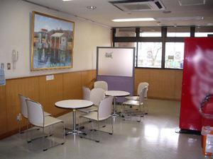 座席近くの壁に油絵が飾られている内牧地区公民館談話室の写真