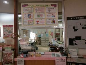 各種掲示物が窓や壁に掲示されている事務室窓口の写真