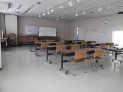 白を基調とした武里地区公民館会議室1（机といすを置いた状態）の写真