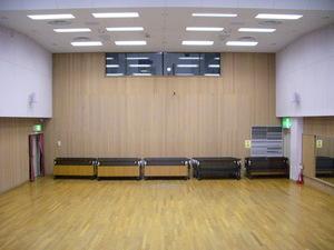 自然な雰囲気の木製の床と壁が特徴的な内牧地区公民館講堂の写真