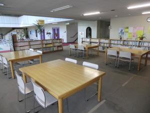 モノトーンの部屋に木製の机と本棚が用意された落ち着いた雰囲気の幸松地区公民館図書コーナーの写真