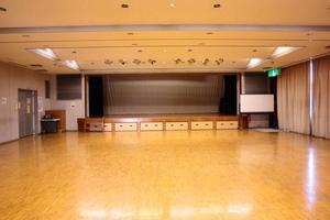 広々としたフロアに講堂ステージが用意されている区公民館講堂の写真