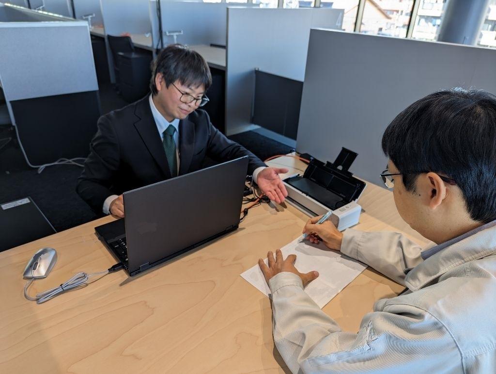 職員が作成した申請書を確認、署名するイメージ